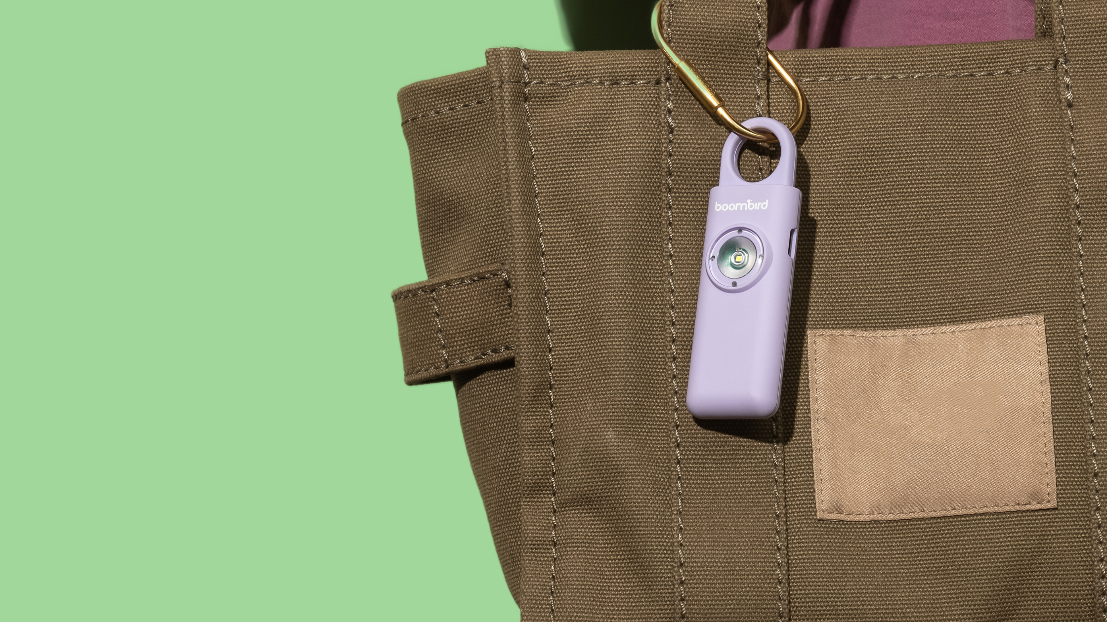 BoomBird personal safety alarm clipped to a woman’s handbag zipper